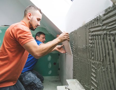 two professional tilers installing large format tiles. home reno